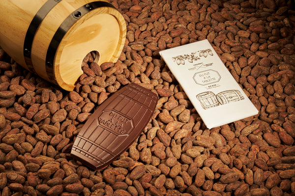 Tablette de chocolat noir à 75% du fut à la tablette Calvados de la distillerie Coquerel sur des fèves sortant d'un fut