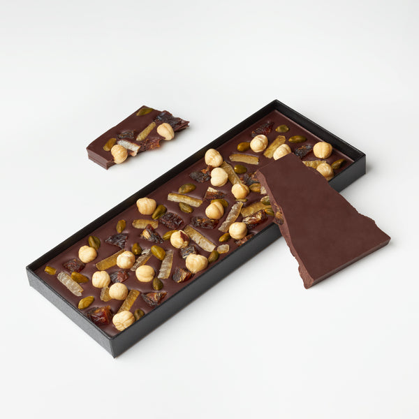 Plaquette gourmande au chocolat noir avec des dattes, des pistaches, des noisettes et des écorces de citrons confits