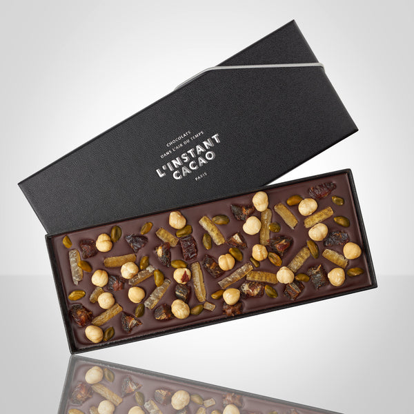 Plaquette gourmande au chocolat noir avec des dattes, des pistaches, des noisettes et des écorces de citrons confits