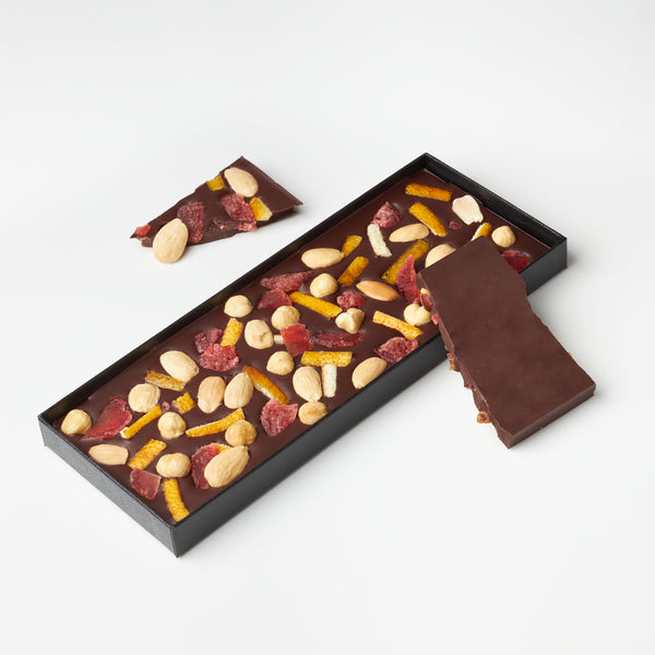 Plaquette gourmande au chocolat noir avec des fraises, des amandes, des noisettes et des écorces d'oranges confites