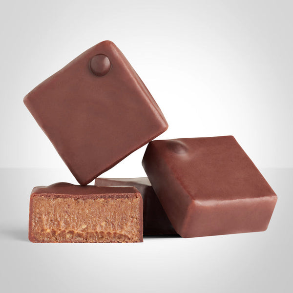 Bonbons pralinés en chocolat au lait et aux noix de pécan de L'Instant Cacao et bonbon coupé en deux